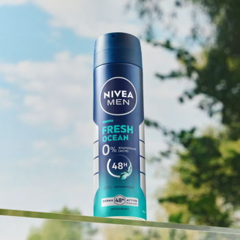NIVEA MEN Fresh Ocean dezodorant, niebiesko-turkusowa butelka w sprayu, widok z przodu na tle nieba i zieleni.