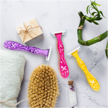 Trzy maszynki BIC Miss Soleil (fioletowa, różowa, żółta) z kwiatowym wzorem, pasek nawilżający. Na marmurze z ręcznikiem i bambusem.