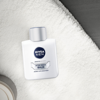 NIVEA MEN Sensitive Regenerujący Balsam, biała butelka z niebieskim logo, na białym ręczniku, z góry.