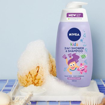 Fioletowa butelka NIVEA Kids 2w1 Shower & Shampoo z pompką stoi na białej tacy, obok spieniona gąbka.