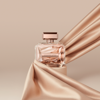 Jennifer Lopez Promise kwiatowo-drzewno-piżmowa woda perfumowana w butelce, otulona różowo-złotym jedwabiem.