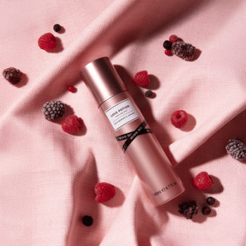 Miss So...? Love Potion mgiełka do ciała w różowo-złotej butelce z czarną wstążką, leży na różowej tkaninie z jagodami.