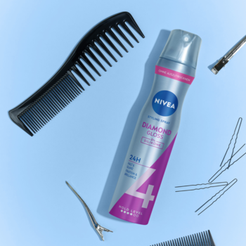 Srebrny lakier NIVEA Diamond Gloss 24h z różem, czarny grzebień i spinki do włosów na jasnoniebieskim tle.