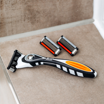 Zestaw golarki BIC Hybrid 5 Flex: czarno-pomarańczowa rączka i dwa 5-ostrzowe wymienne wkłady, na beżowym tle.