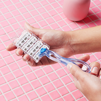 Zbliżenie: dłonie trzymają 4 wymienne wkłady BIC Click Soleil 3 z 3 ostrzami, aloesem i wit. E, na różowym tle.