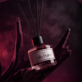 Pachnące patyczki Ellie Pure w szklanej butelce, na tle ciemnego dymu i drewna, ujęcie pod kątem.