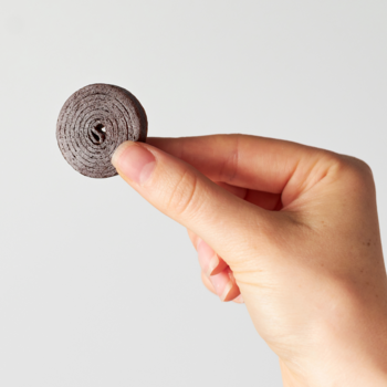 Zbliżenie: dłoń trzyma ciemny, spiralny owocowy rolls Bob Snail, zdrową przekąskę bez dodatku cukru.