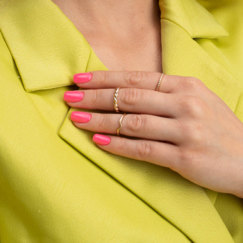 Zbliżenie na dłoń z paznokciami pomalowanymi różowym lakierem hybrydowym Friendly Magenta, noszącą pierścionki.
