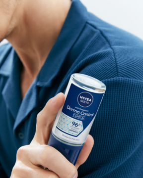 Męski antyperspirant NIVEA MEN Derma Dry Control roll-on, niebiesko-biały, trzymany w dłoni mężczyzny.