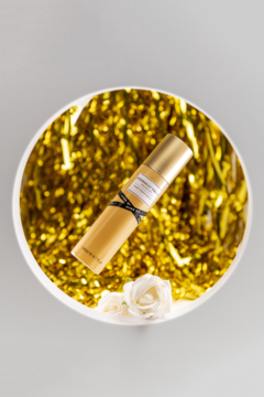 Mgiełka perfumowana Eternally Yours w złotej butelce, w białej misie ze złotą folią i białymi różami, widok z góry.