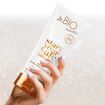Biała tuba balsamu brązującego beBIO "start your safe tanning", trzymana w dłoni, widok z przodu.