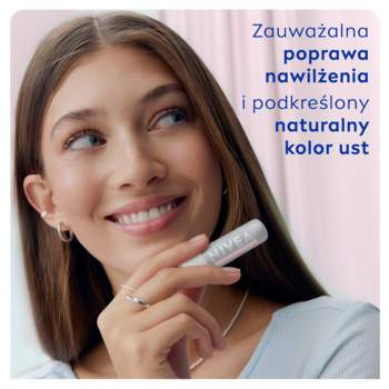 Młoda kobieta uśmiecha się, trzymając w dłoni biały balsam NIVEA Hyaluron Rose do ust, podkreślający naturalny kolor.