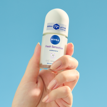 NIVEA Fresh Sensation antyperspirant roll-on, 72h, kwiaty i jagody, trzymany w ręce na błękitnym tle.