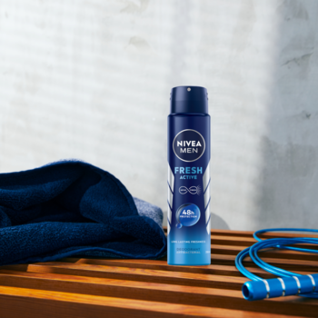NIVEA MEN Fresh Active 48h dezodorant w niebieskim sprayu, na drewnianej ławce z ręcznikiem i skakanką.