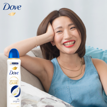 Uśmiechnięta kobieta z gładkimi pachami, z butelką Dove Advanced Care 72h ochrony w sprayu.