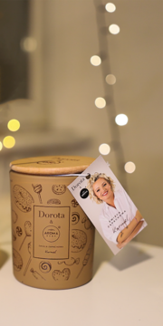 Widok z przodu brązowej świecy zapachowej Dorota & Aroma Home Karmel z grafikami słodyczy i zawieszką.