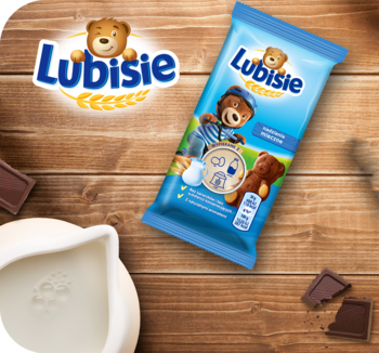 Ciastko Lubisie z nadzieniem mlecznym w niebieskim opakowaniu z misiem, na drewnianym tle z mlekiem i czekoladą.
