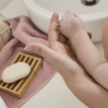 Zbliżenie na dłoń myjącą rączkę dziecka mydłem Bambino, z widocznym mydłem w kostce i ręcznikiem.