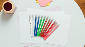 Flamastry Bic Kids: 10 kolorowych wymazywalnych markerów i 2 wymazywacze, ułożone wachlarzowo na białych kartkach.