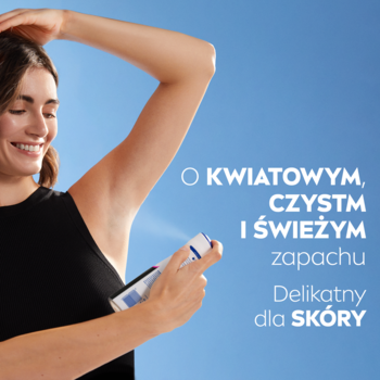 Uśmiechnięta kobieta aplikuje antyperspirant NIVEA Black & White Clear spray na pachę, błękitne tło.