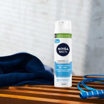Żel do golenia NIVEA MEN Sensitive Cool 200ml w białej butelce, na drewnianej ławce z ręcznikiem i skakanką.