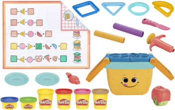 Zestaw Play-Doh z 6 tubami ciastoliny, żółtym pojemnikiem, foremkami i matą edukacyjną, widok z góry.