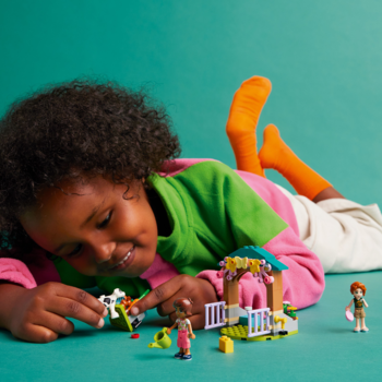 Dziewczynka bawi się klockami Lego Friends Szopa cielątka Autumn z szopą, mini-laleczkami i zwierzętami.