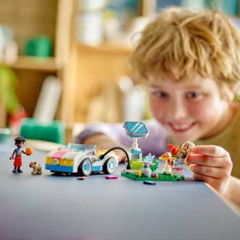 Chłopiec bawi się zestawem LEGO Friends: samochodem elektrycznym, stacją solarną, minilaleczkami i psem.