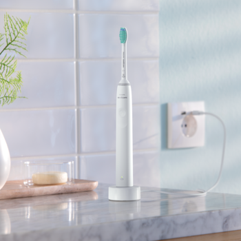 Biała elektryczna szczoteczka soniczna Philips Sonicare na ładowarce, w nowoczesnej łazience.