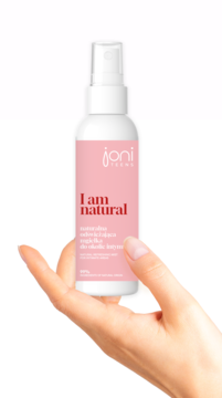 Ręka trzyma białą butelkę JONI TEENS "I am natural" naturalnej odświeżającej mgiełki intymnej z różową etykietą.