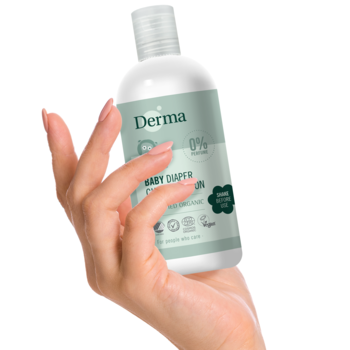 Ręka trzyma białą butelkę Derma Eco Baby Emulsja 3w1 do pieluszki, z zieloną etykietą na białym tle.
