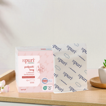 Różowe pudełko podpasek npuri by Bambiboo na noc i biała, wzorzysta owijka na bambusowym blacie.