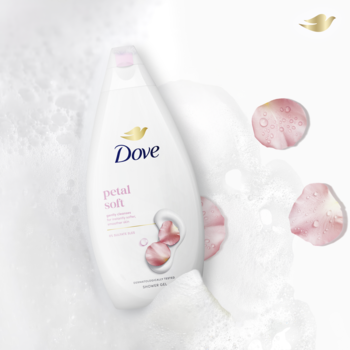 Biały żel pod prysznic Dove Petal Soft, z różowym napisem i motywem płatków, w otoczeniu piany i różowych róż.
