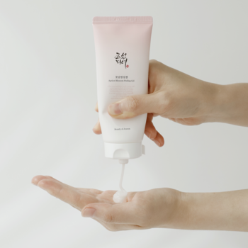 Beauty of Joseon Apricot Blossom Peeling Gel, bladoróżowa tubka, dłonie wyciskają biały żel gommage.