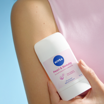 Zbliżenie na NIVEA Pearl & Beauty Antyperspirant w sztyfcie (72h ochrona, perły), trzymany przez dłoń przy ramieniu.