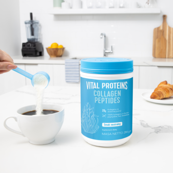 Ręka wsypuje białe peptydy kolagenu Vital Proteins z miarki do kawy, obok stoi biało-niebieska tubka produktu.