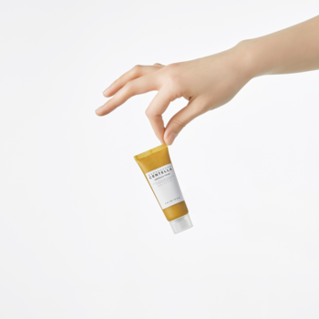 Ręka trzyma małą, żółtą tubkę pianki do mycia twarzy Skin1004 Centella Ampoule Foam travel size.