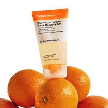 Żel do twarzy Carbon Theory z wit. C i kofeiną w tubce transparentno-pomarańczowej, stojący na pomarańczach.