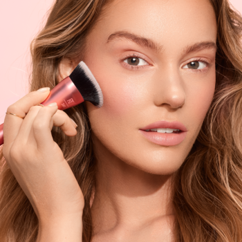 Zbliżenie: Kobieta używa pędzla Real Techniques Snatch + Sculpt Contour z szarym włosiem do modelowania policzka.