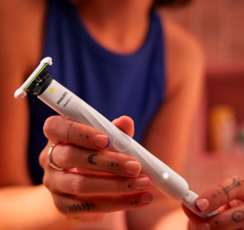 Zbliżenie na białą maszynkę Philips OneBlade Intimate w dłoniach, z zielonym ostrzem, do wrażliwych miejsc.