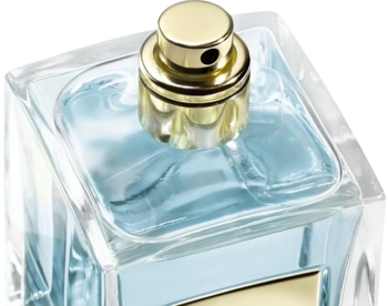 Perfumy męskie w szklanej butelce z niebieskim płynem, zbliżenie na złotą nakrętkę i rozpylacz, ukośne ujęcie.