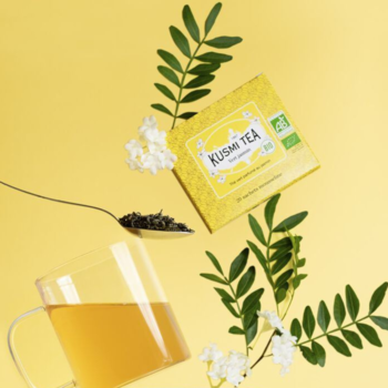 Kusmi Tea: żółte pudełko organicznej herbaty jaśminowej, filiżanka, liście i białe kwiaty na żółtym tle.