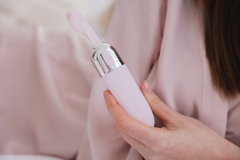 Różowy masażer Sleek Cheer Beautifly w dłoni, z błyszczącym srebrnym elementem. Gładka, ergonomiczna obudowa.