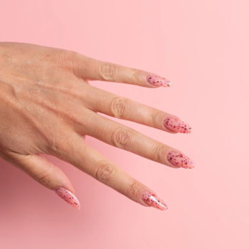 Ręka z paznokciami Semilac w różowy brokat z intensywnie czerwonymi drobinkami, błyszczące wykończenie.