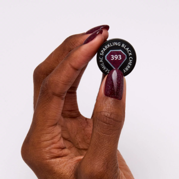 Dłoń trzyma wzornik brokatowego lakieru hybrydowego Semilac 393 Sparkling Black Cherry, z pomalowanymi paznokciami.