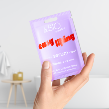 Fioletowa saszetka beBIO Cosmetics liftingującego serum 'easy lifting' ze spilantolem, trzymana w dłoni.
