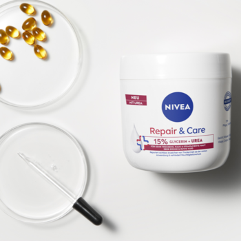 Biały słoik kremu NIVEA Repair & Care 15% Glycerin+Urea na białym tle, obok dwie szalki Petriego.