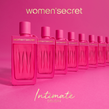 Women's Secret Intimate Delight, różowy flakon z falistym zdobieniem na pierwszym planie, rząd perfum w tle.
