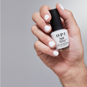 Dłoń z białymi paznokciami trzyma buteleczkę białej odżywki OPI Nail Envy Alpine Snow na jasnym tle.