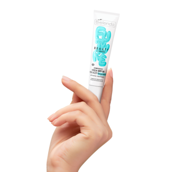 Krem pod oczy SPF 50 w białej tubce z niebieskim napisem, trzymany pionowo w dłoni, widok z przodu.